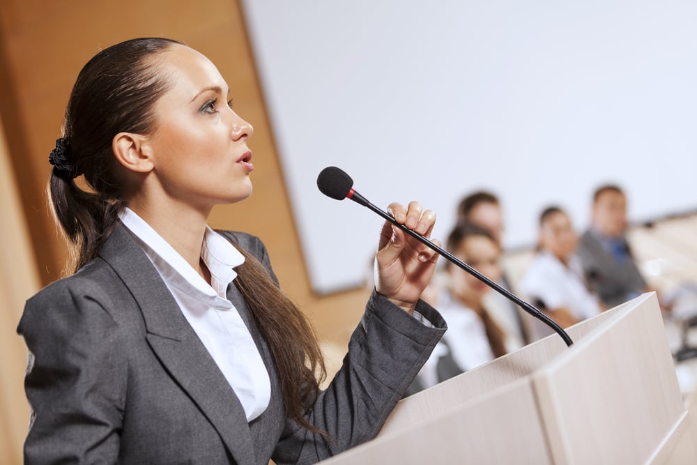 Businesswoman standing on stage and reporting for audience-1