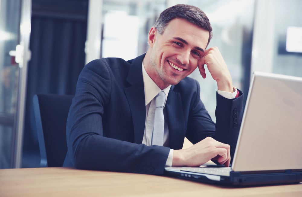 Cheerful businessman sitting with laptop at office