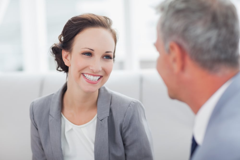 Cheerful businesswoman listening to her workmate talking in bright office-1