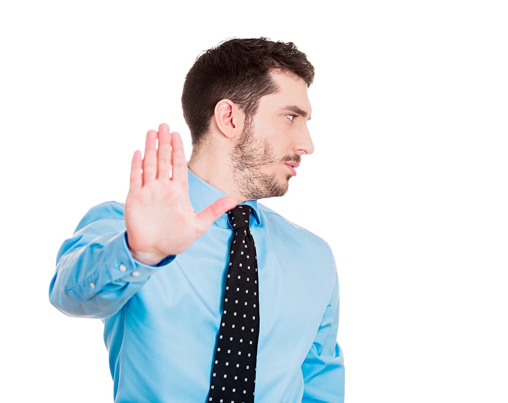 Closeup portrait of young handsome, grumpy man with bad attitude giving talk to hand gesture with palm outward, isolated white background. Negative emotions, facial expression feelings, body language