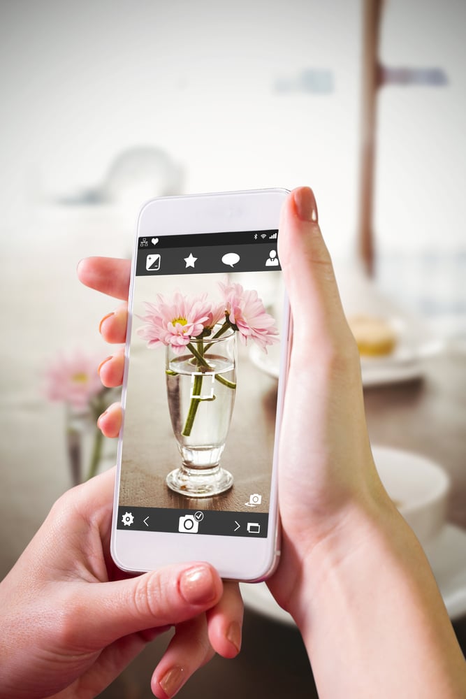 Hand holding smartphone against latte and coffee on table