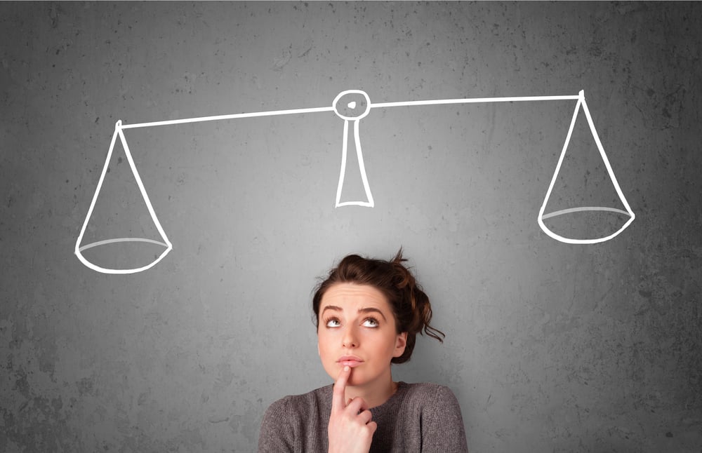 Pretty young lady taking a decision with scale above her head-1