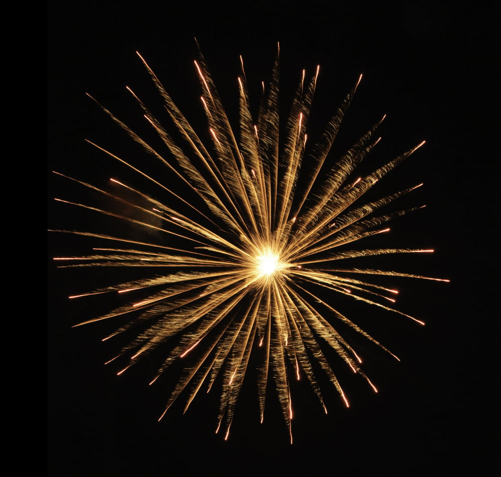 Round burst of orange fireworks with feathery motion blur and white-hot core of explosion