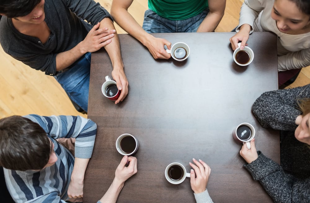 Students sitting around table drinking coffee in college cafe-1