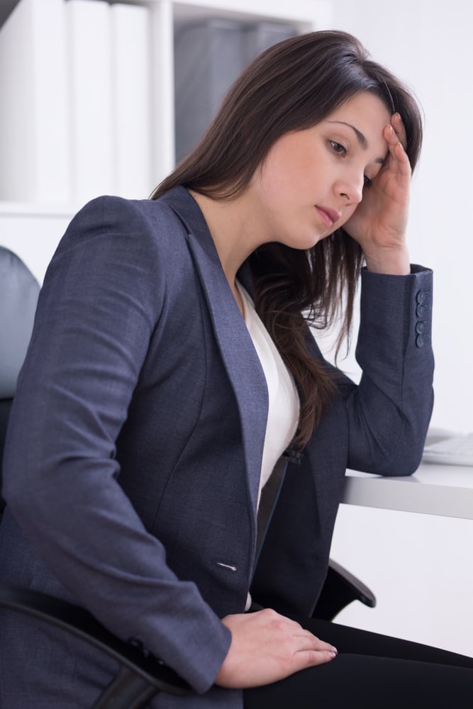 Tired woman with headache sitting beside desk at office