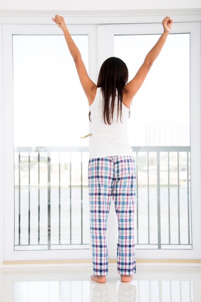 Woman at home just waking up and looking through the window