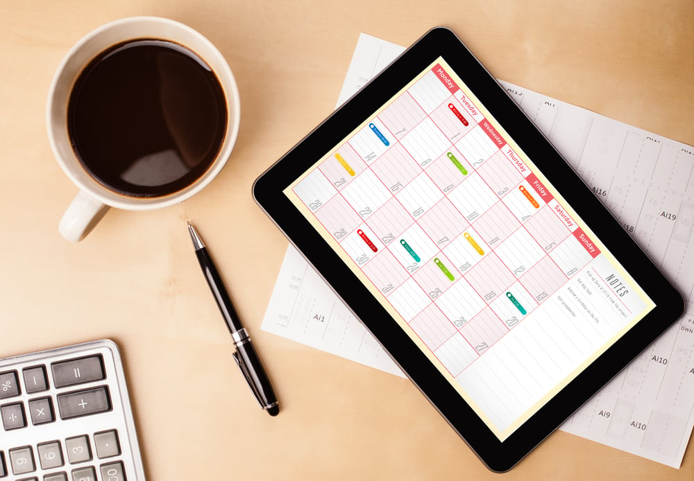 Workplace with tablet pc showing calendar and a cup of coffee on a wooden work table close-up-2