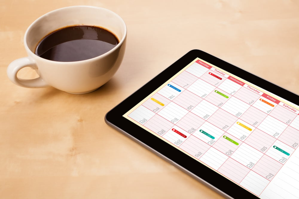 Workplace with tablet pc showing calendar and a cup of coffee on a wooden work table close-up-Aug-23-2023-03-37-44-3193-PM
