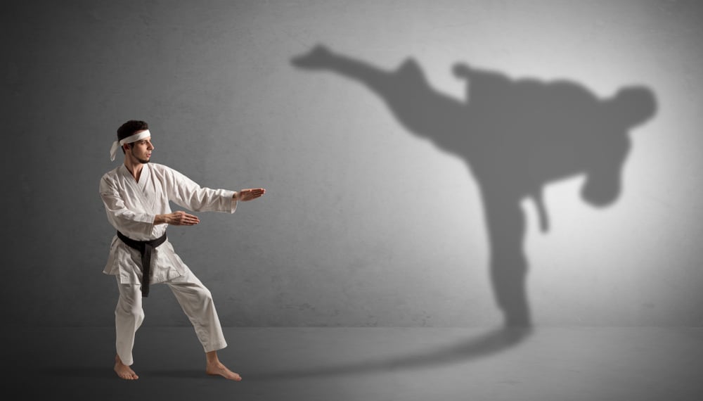 Young karate man confronting with his own shadow