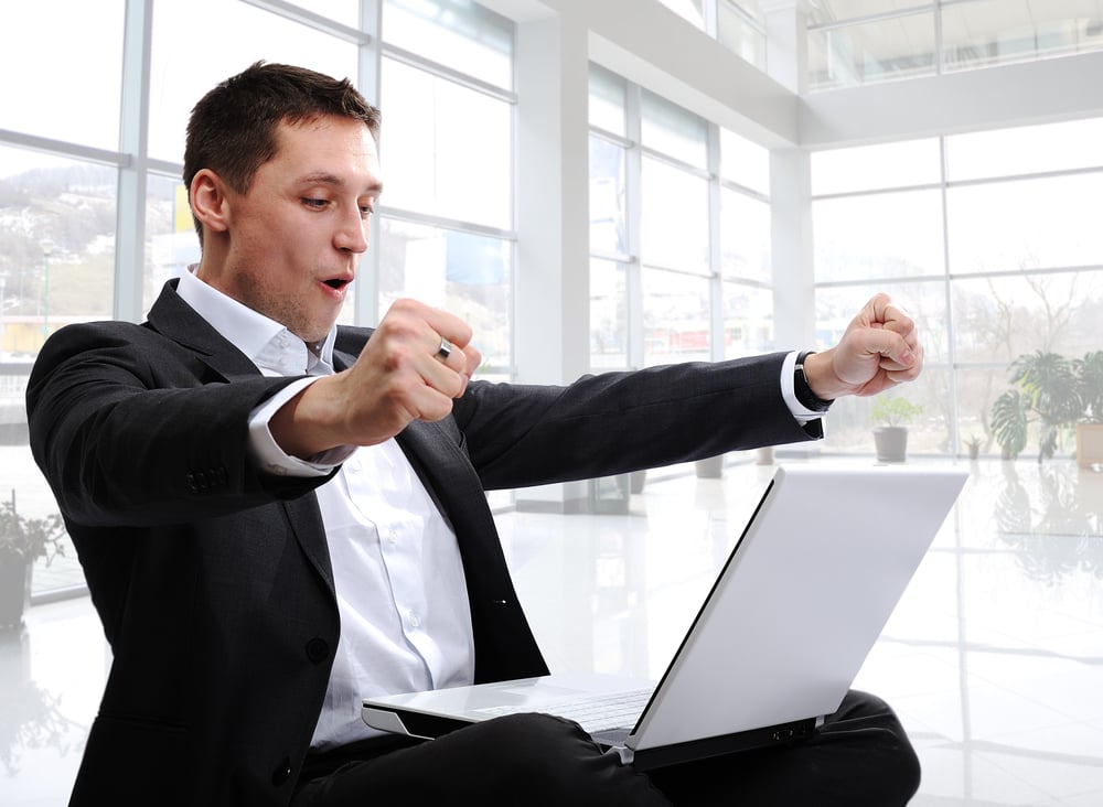 successful man with laptop in modern white office with glass around