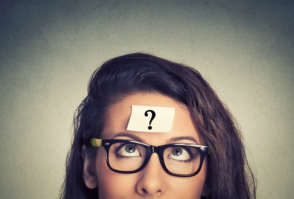 thinking woman with question mark on gray wall background